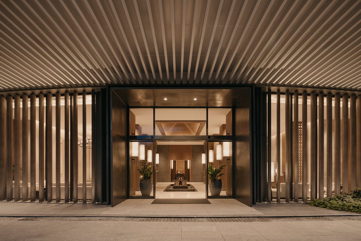 Elegant entrance of a luxury residential development with warm lighting, modern architectural details, and a refined interior visible inside