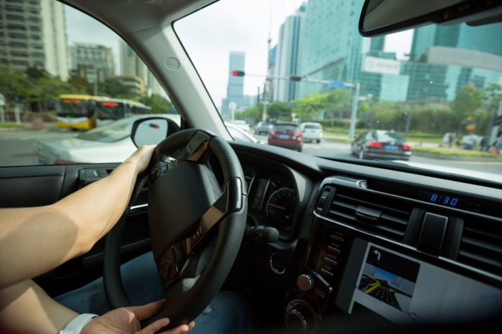 Driver navigating through a busy Mandaluyong city road with high-rise buildings nearby