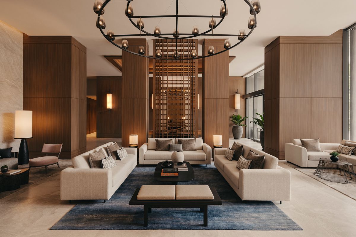 Modern lobby lounge at Shang Residences at Wack Wack with neutral-toned sofas, wood-paneled walls, and a large decorative chandelier.