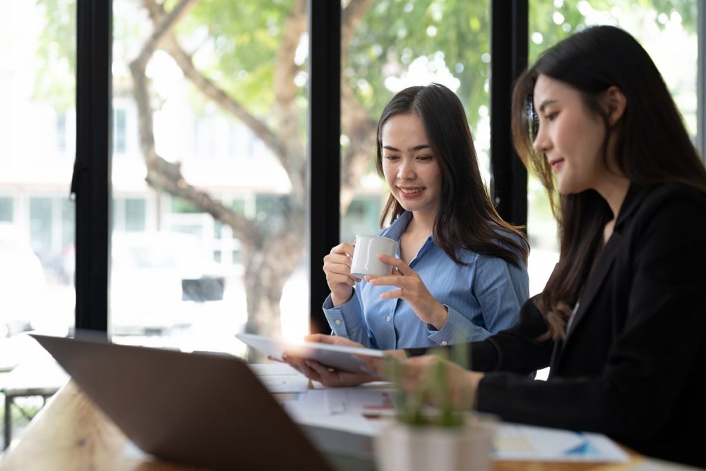 Two women reviewing property investment information on a laptop, representing overseas investors evaluating long-term value and returns