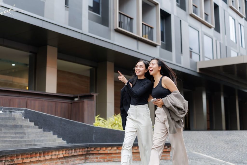 Two women walking outside a modern residential building, highlighting the convenience and lifestyle benefits of a well-located property