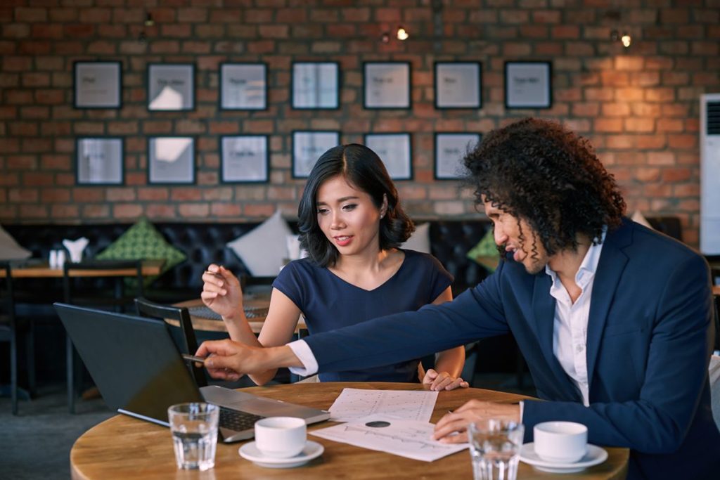 Property buyer reviewing investment documents and information with an advisor while discussing a potential real estate purchase