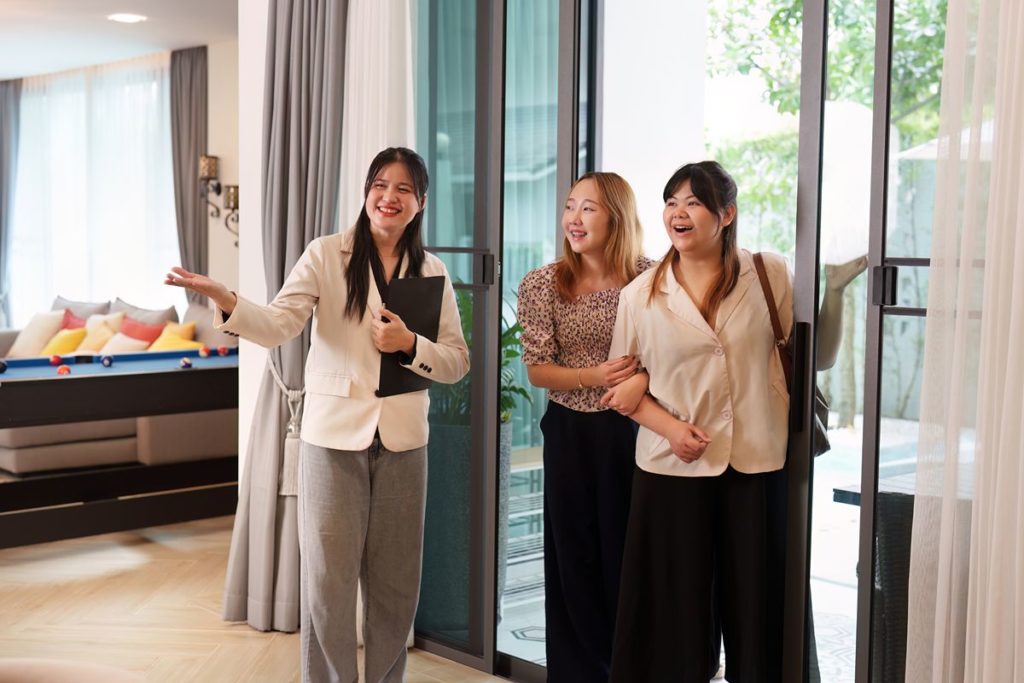 Property consultant showing two prospective buyers around a modern condominium residence during a property viewing